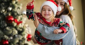 Mother Holding Toddler Wearing a Christmas cap and christmas sweater